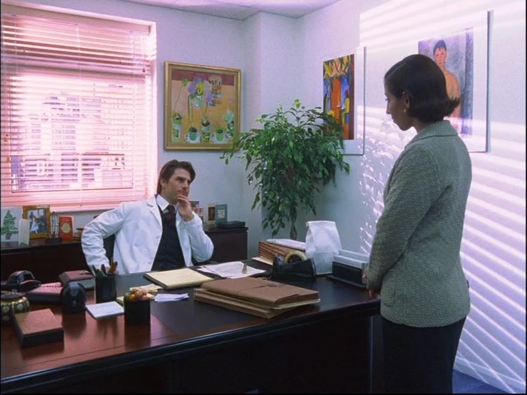 Eyes Wide Shut (1999) movie still: wide — A doctor's consultation room features a large wooden desk and two framed paintings on walls. A man in a…