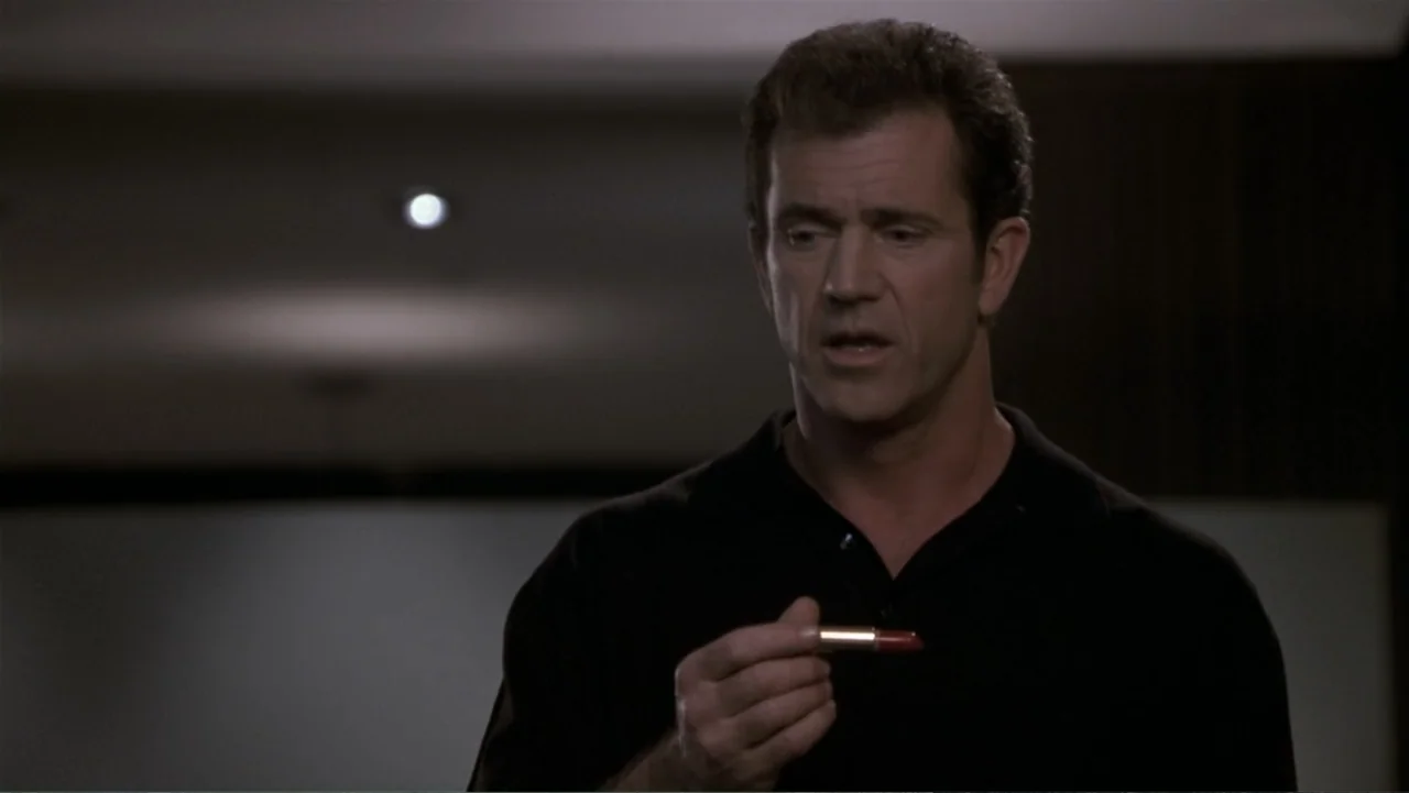 What Women Want (2000) movie still: medium — A dark indoor space with blurred wall elements and dim overhead light. A man in a black shirt holds a…