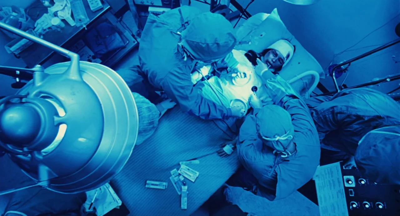 The Crow (1994) movie still: wide — An operating room lit by a surgical light with a patient undergoing medical treatment. Surgical staff surround…