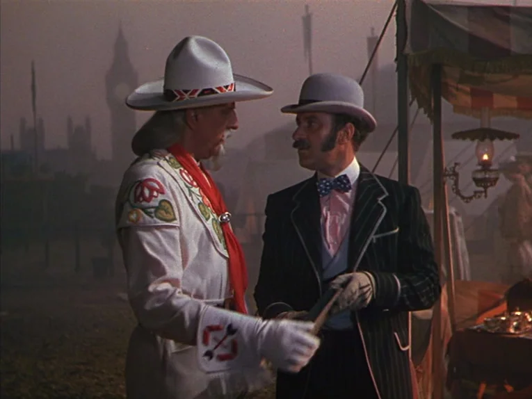 Annie Get Your Gun (1950) movie still: medium — An outdoor fairground at dusk features a silhouette of the Big Ben clock tower. Two men in period…