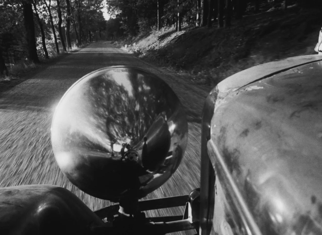 Pearls of the Deep (1965) movie still: closeup — A vintage car headlight reflects the surrounding trees while traveling down a dirt road. The…