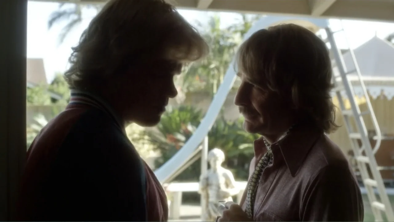 Behind the Candelabra (2013) movie still: medium — An outdoor patio area with a white ladder and a statue in the background. Two men in 1970s attire…