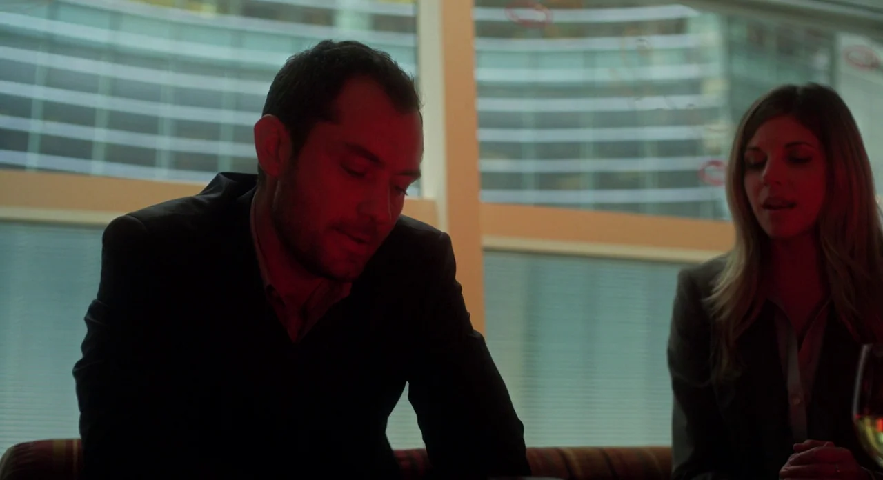 Side Effects (2013) movie still: medium — A man and woman sit in a restaurant booth with a large window behind them. The interior is dark and lit…