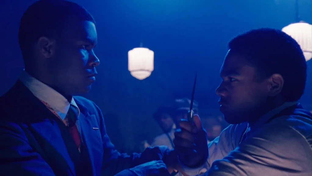 Honeydripper (2007) movie still: medium — A dimly lit room bathed in blue light with overhead globe fixtures. Two men stand close together in a…