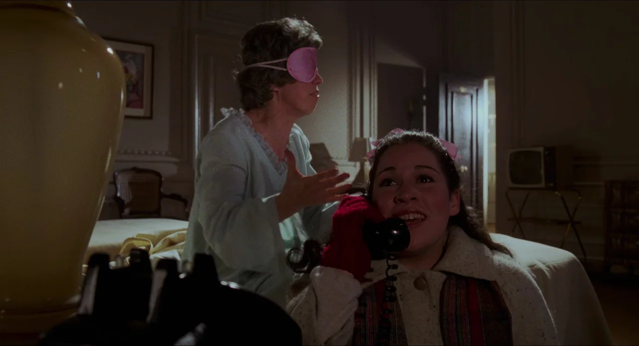 I Wanna Hold Your Hand (1978) movie still: medium — A dimly lit hotel room with classic decor including a large bedside lamp and television. One…