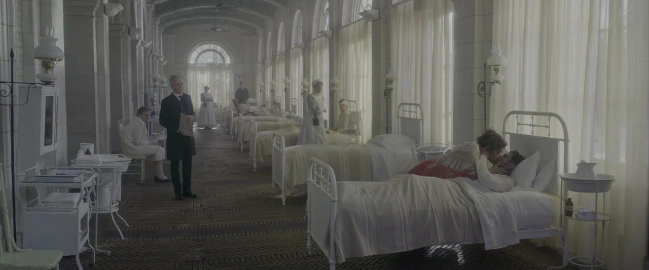 The Greatest Showman (2017) movie still: wide — A long, white-tiled hospital ward features rows of metal beds and arched windows. Patients lie in…