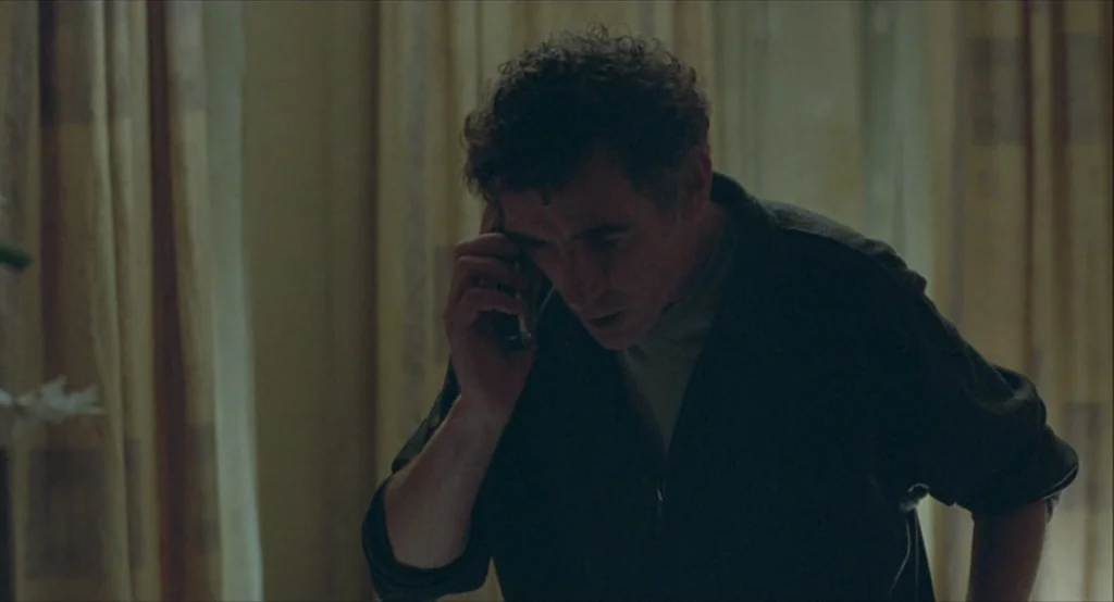Looking for Eric (2009) movie still: medium — A dimly lit room features drawn curtains draped in the background behind the subject. A man in a dark…