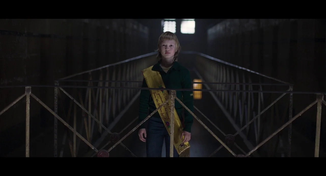 True History of the Kelly Gang (2019) movie still: fullbody — A long, dimly lit institutional walkway features metal railings on both sides. A young…
