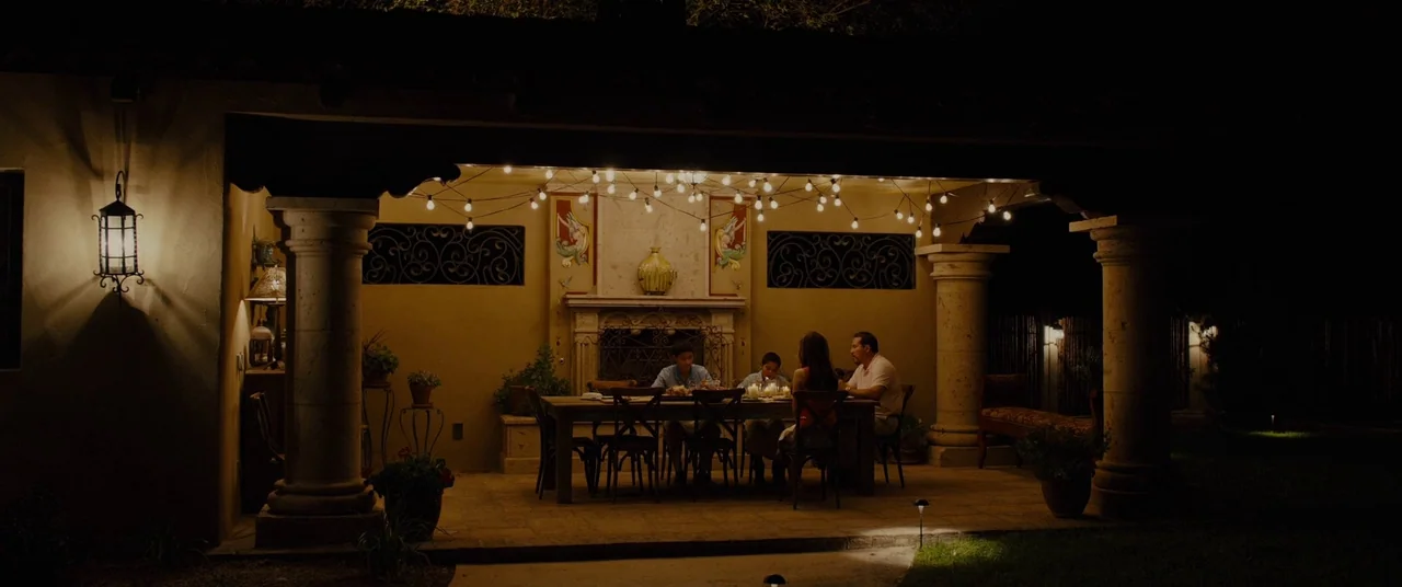 Sicario (2015) movie still: wide — A covered outdoor terrace features stone columns and a central fireplace decorated with artwork. Four people…