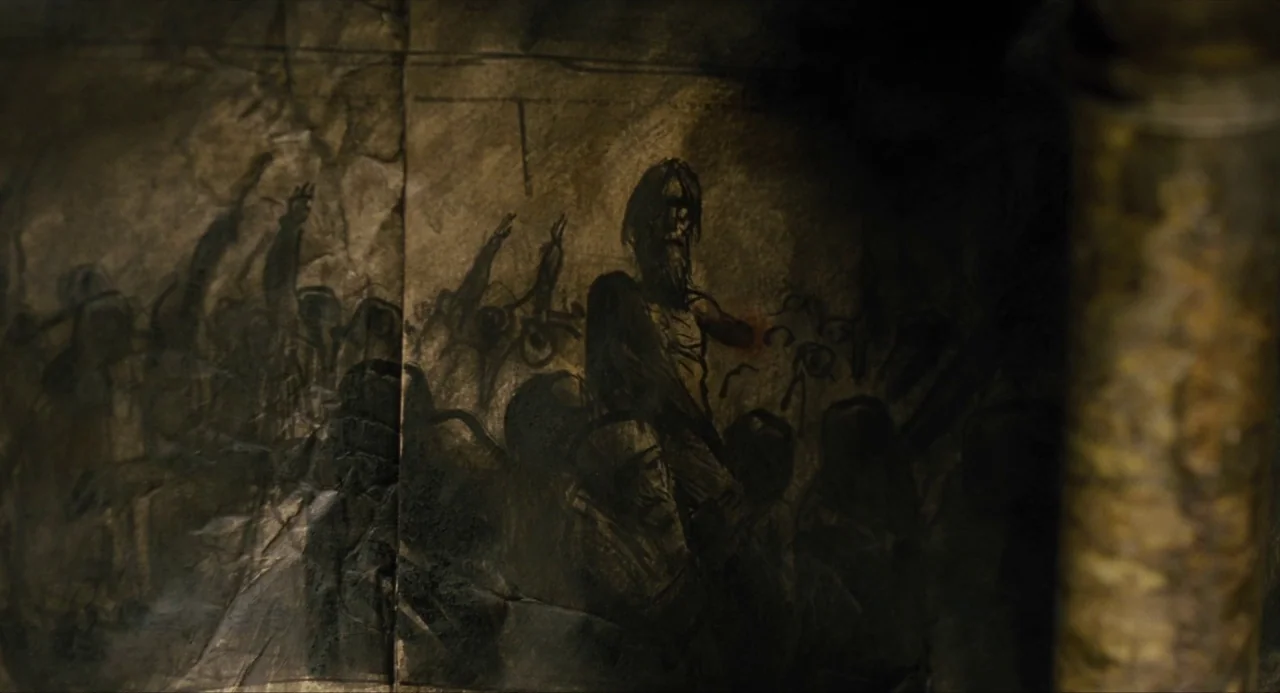 Snowpiercer (2013) movie still: closeup — A textured piece of aged, folded paper contains a dark, charcoal-style figurative illustration. The…