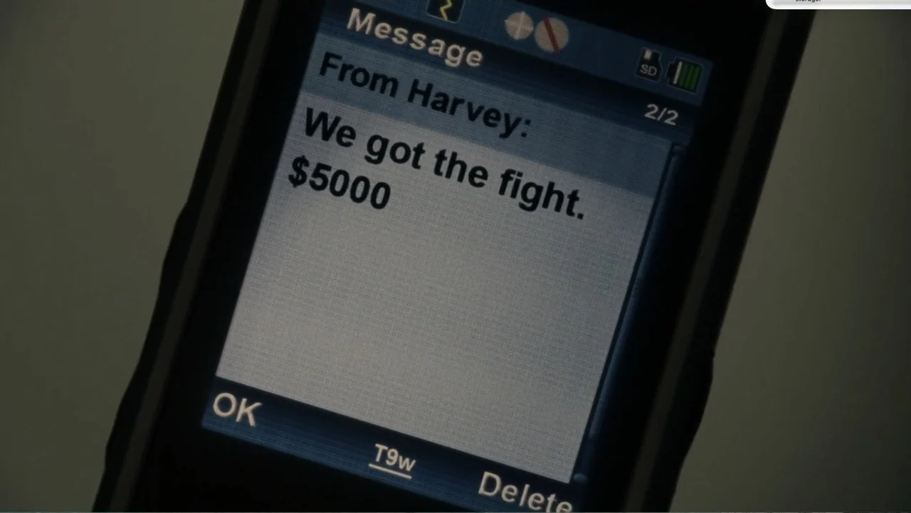 Fighting (2009) movie still: closeup — A close-up view of a mobile phone screen showing a text message from Harvey. The message reads, "We got the…