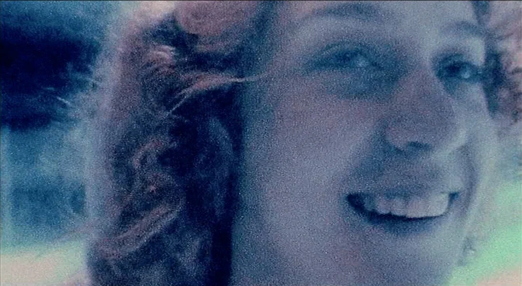 Julien Donkey Boy (1999) movie still: closeup — An outdoor setting is visible with a soft-focus background of blurred foliage. A young woman with…