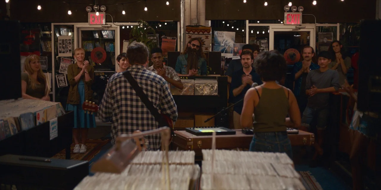 Hearts Beat Loud (2018) movie still: medium — A crowded record store interior features rows of vinyl bins and warm string lights. A musician…