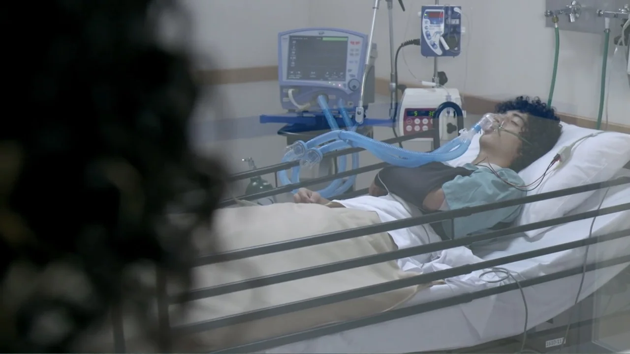 Loco Love (2003) movie still: medium — A clinical hospital room with medical equipment and a patient connected to a ventilator. A young male patient…
