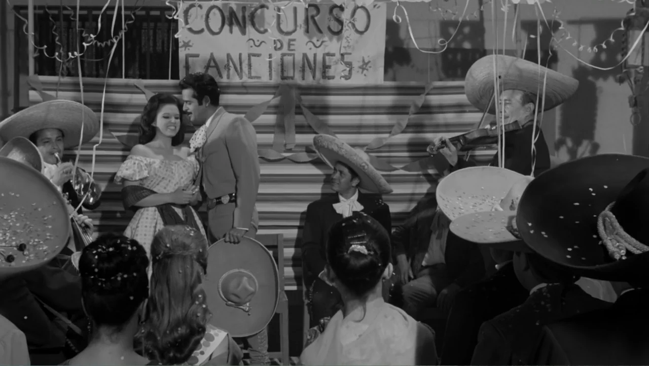 Escuela para solteras (1965) movie still: medium — A room decorated for a song contest features a hand-painted banner and streamers. A man and woman…