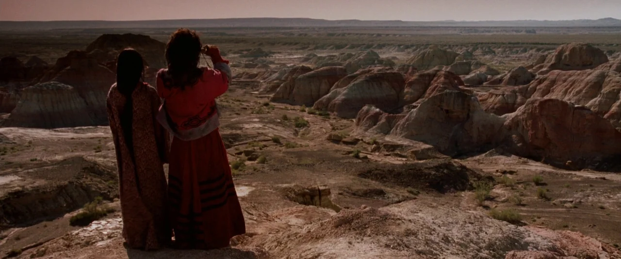 Crouching Tiger, Hidden Dragon (2000) movie still: wide — A vast arid desert landscape features layered rock formations with red and tan hues. Two…