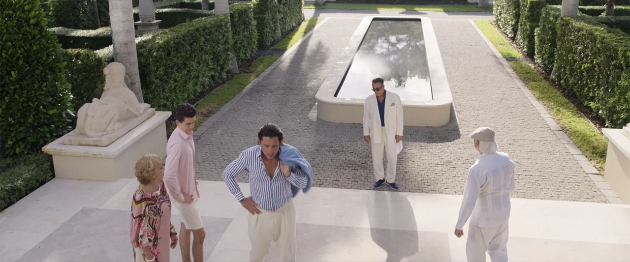Father of the Bride (1991) movie still: wide — A stone-paved outdoor courtyard features a long rectangular water feature and trimmed hedges. Four…