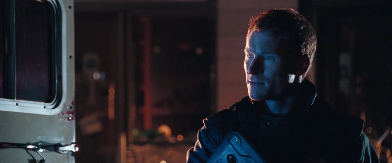 Resident Evil: Apocalypse (2004) movie still: medium — A man in tactical gear stands in the dark next to a vehicle door. He watches a screen that…