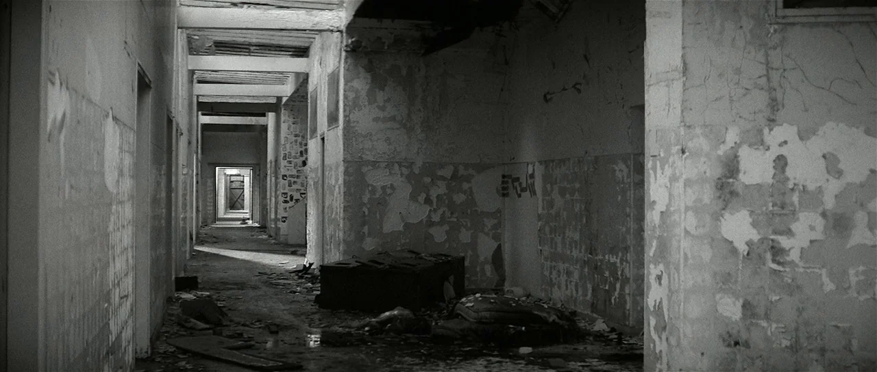 The Last Battle (1983) movie still: establishing — A long, decaying corridor features peeling plaster walls and debris scattered across the floor.…