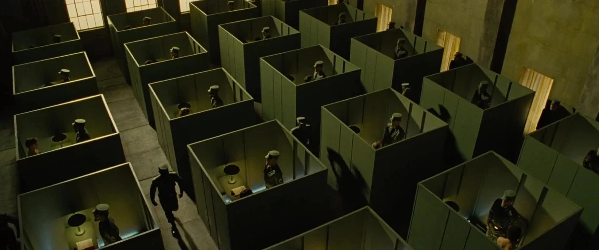 Across the Universe (2007) movie still: wide — Rows of identical square partitions occupy a large, industrial-looking military facility with high…