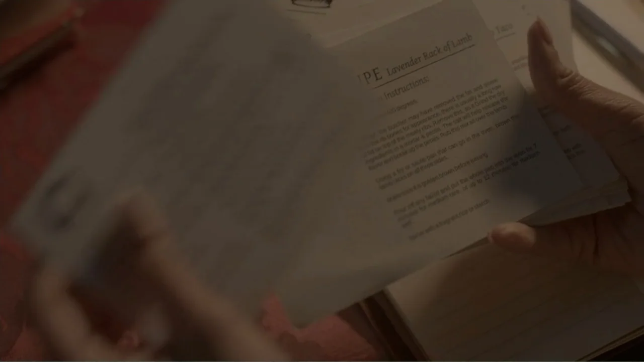 A Pinch of Portugal (2023) movie still: closeup — A close-up of a person holding a stack of printed white recipe cards. One hand holds the deck…