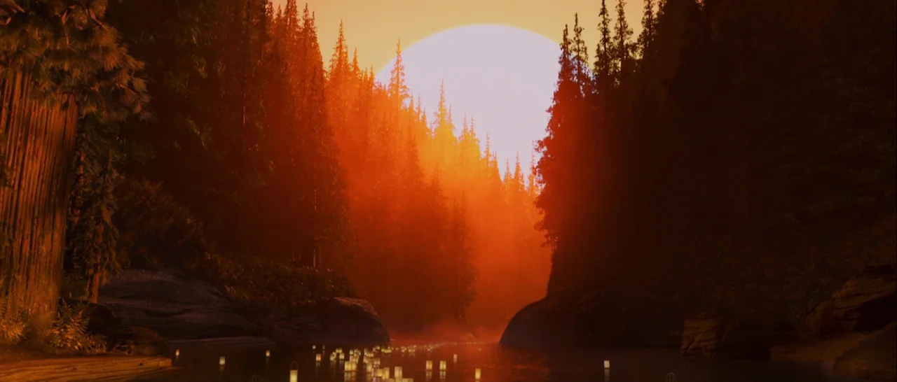 Kubo and the Two Strings movie still: establishing — A dense coniferous woodland flanks a river under a vibrant orange golden hour sun. Small…