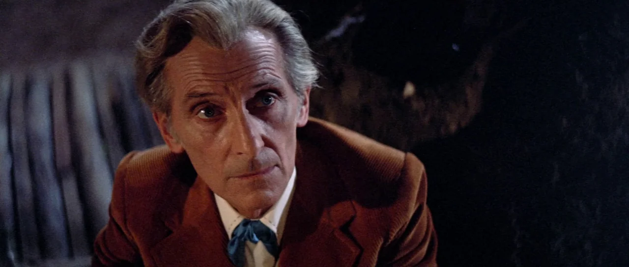The Legend of the 7 Golden Vampires (1974) movie still: closeup — An elderly man sits in a dimly lit interior with soft, directional lighting. He…