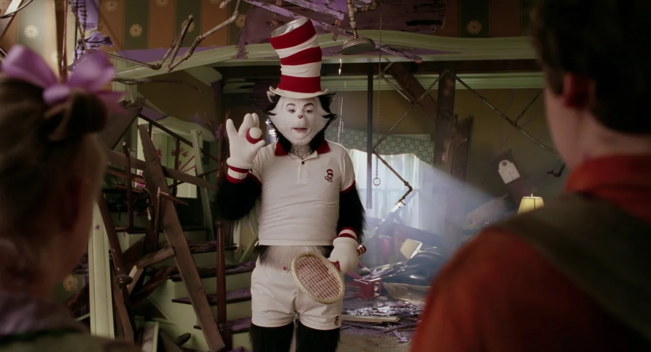 The Cat In The Hat (2003) movie still: medium — A cluttered, partially destroyed room features a tall feline humanoid standing centrally. The figure…