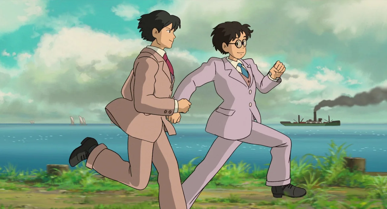 The Wind Rises (2013) movie still: fullbody — A green grassy path runs along a blue ocean under a bright cloudy sky. Two young men in business suits…