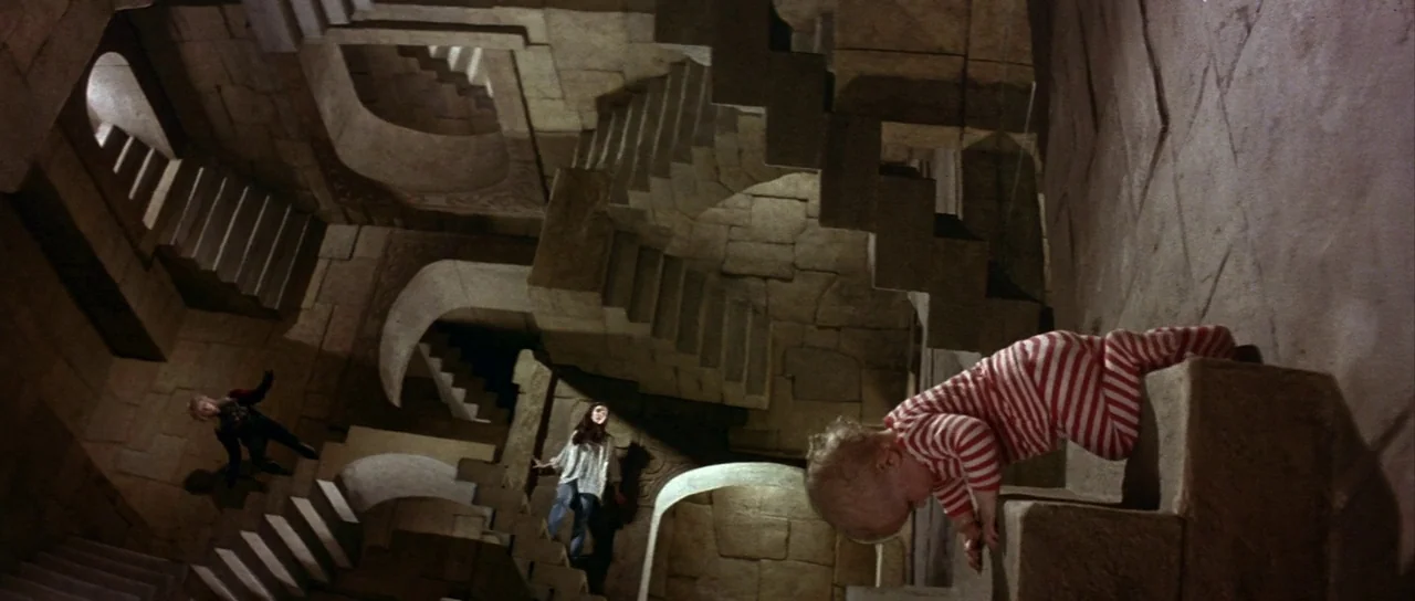 Labyrinth (1986) movie still: wide — An Escher-inspired structure features stone stairs twisting in gravity-defying angles. A baby crawls on a stair…