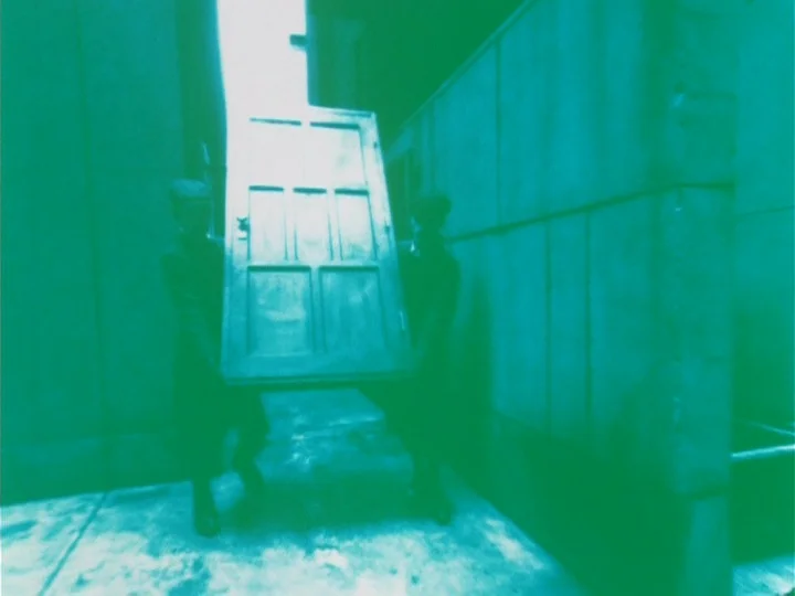 Labyrinth Tale (1975) movie still: fullbody — An outdoor alleyway between two blank walls with a bright opening at the end. Two uniformed figures…