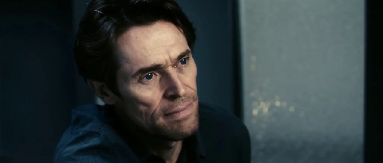 Antichrist (2009) movie still: closeup — A dark indoor space with a smooth, indistinct background wall surface. A middle-aged man with dark hair…
