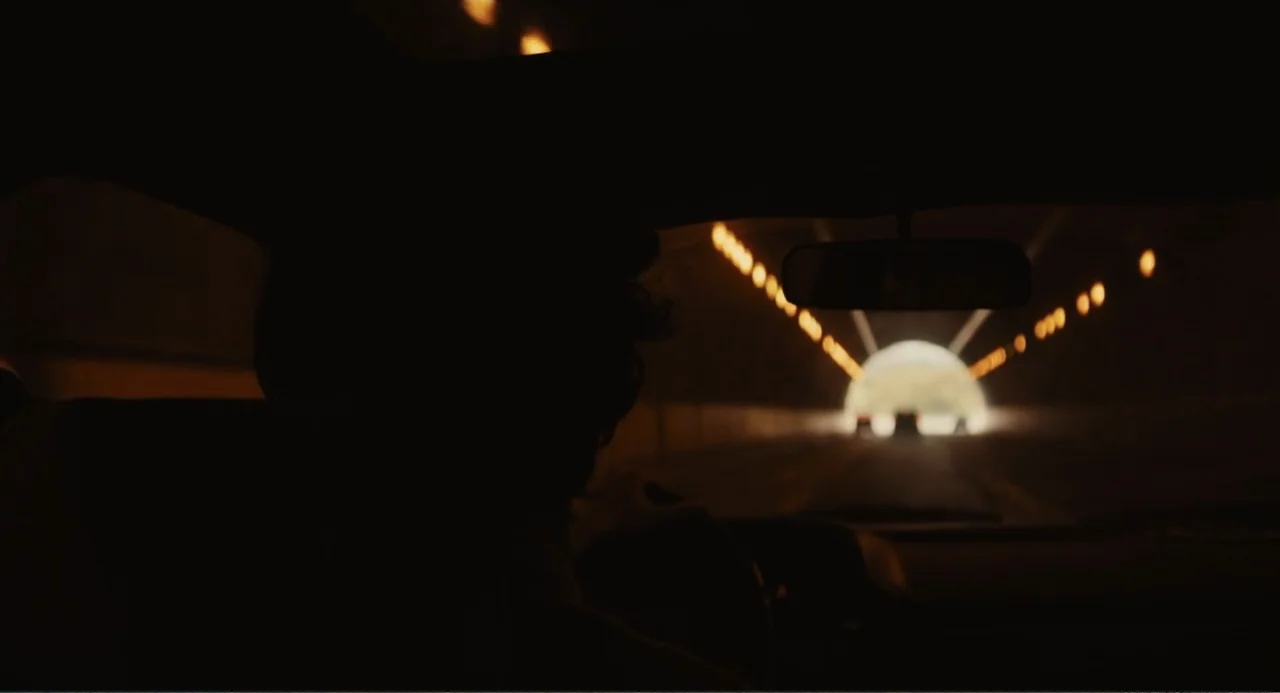 Beautiful Boy (2011) movie still: medium — A dark car interior frames the driver silhouette against a brightly lit tunnel exit. The vehicle moves…