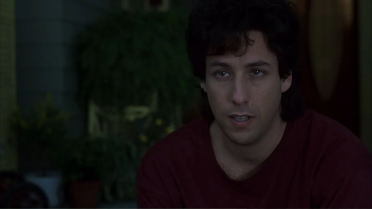 The Wedding Singer (1998) movie still: medium — A dark house porch at night with blurred foliage in the background. A man sits facing forward while…