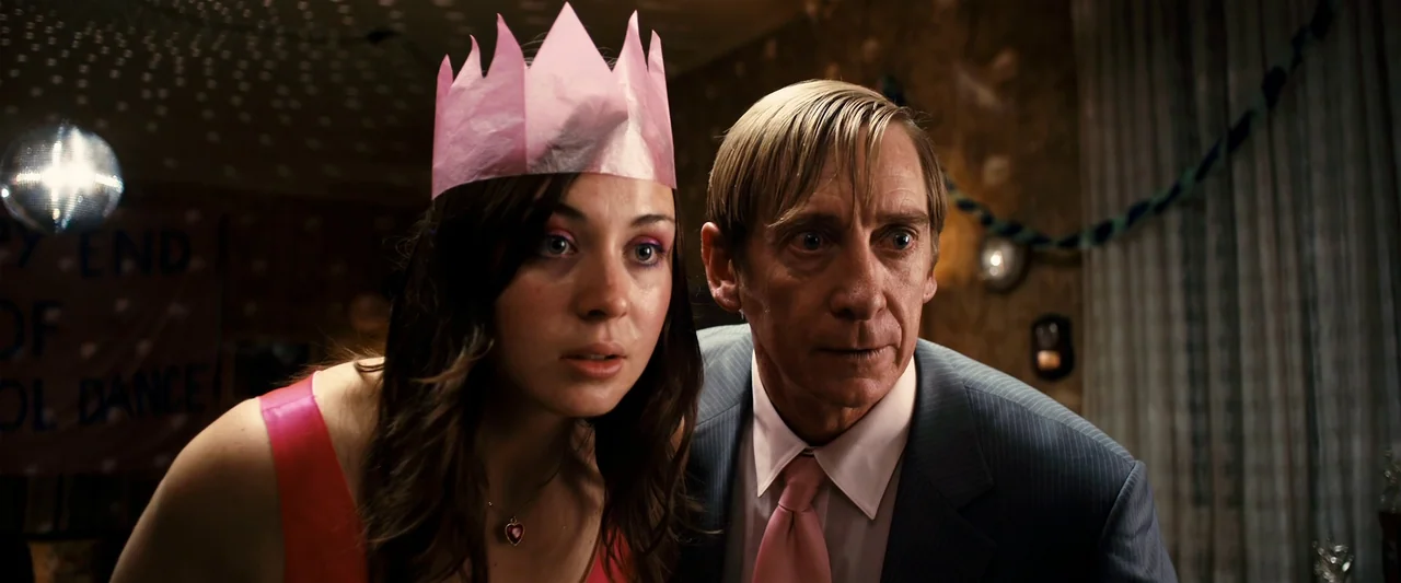 The Loved Ones (2009) movie still: medium — A dimly lit room decorated for a school dance features a disco ball overhead. A young woman wearing a…