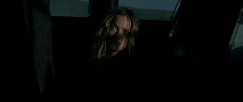 Ondine (2009) movie still: medium — The interior of a dark car at night with a bleak, shadowed landscape visible outside. A young woman with blonde…