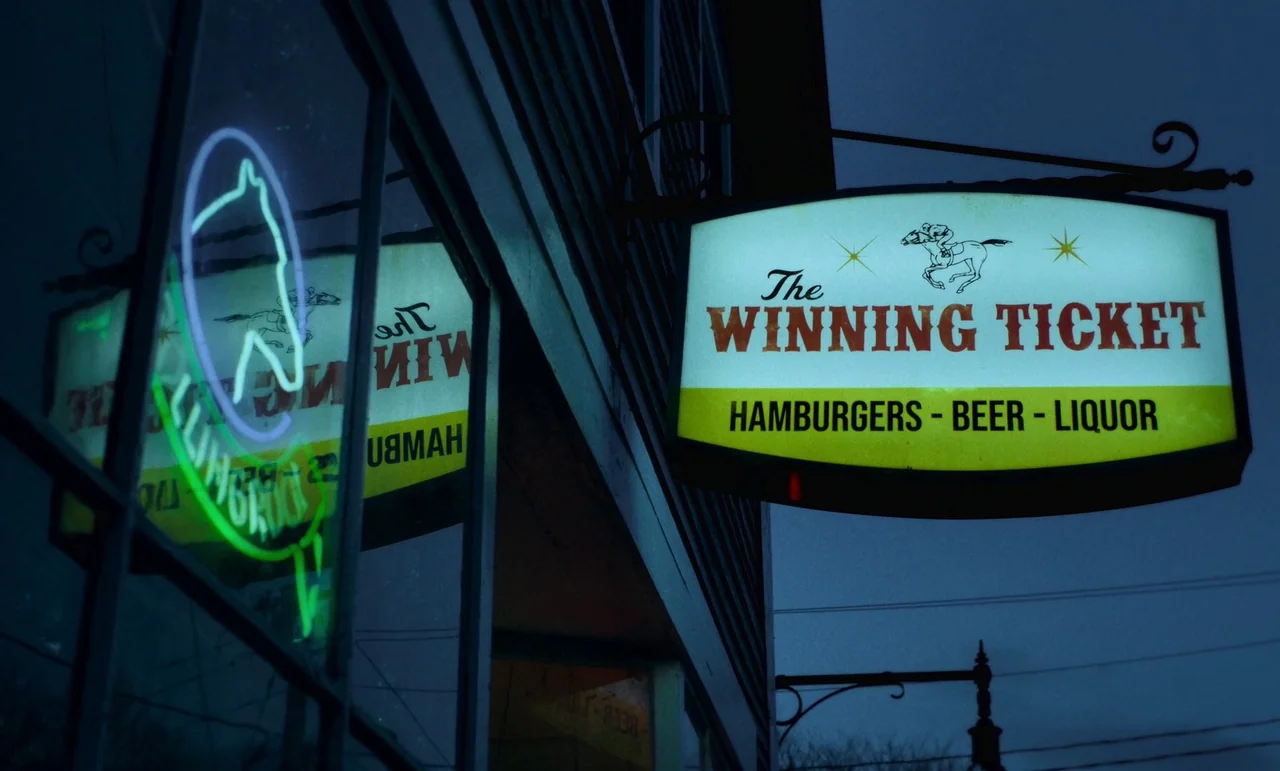 The Holdovers (2023) movie still: wide — A rectangular illuminated business sign hangs above a dark building exterior at night. A neon light in the…