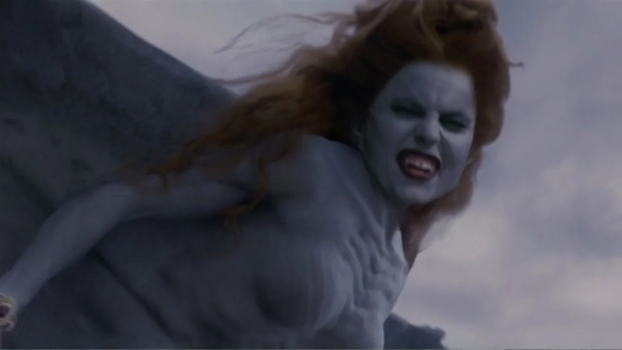 Van Helsing (2004) movie still: closeup — An airborne creature with grey skin and red hair navigates a grey, overcast sky. The subject glides…