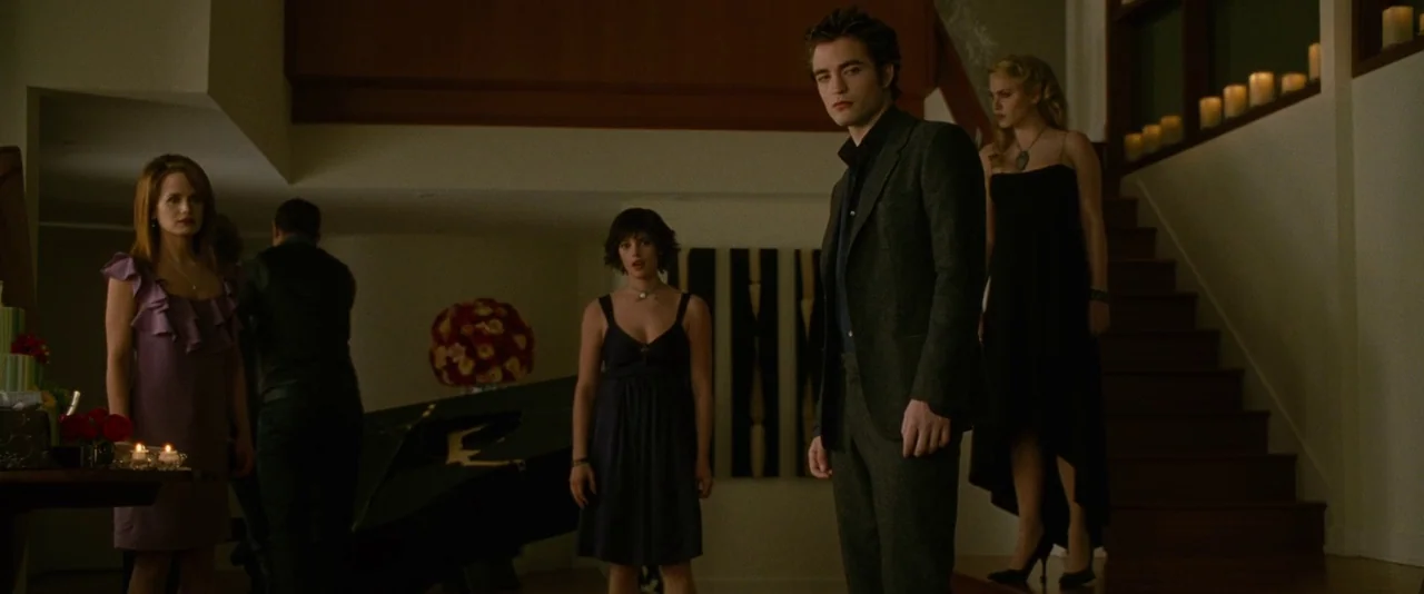 The Twilight Saga: New Moon (2009) movie still: fullbody — A spacious, dimly lit modern room features a dark staircase adorned with lit candles.…