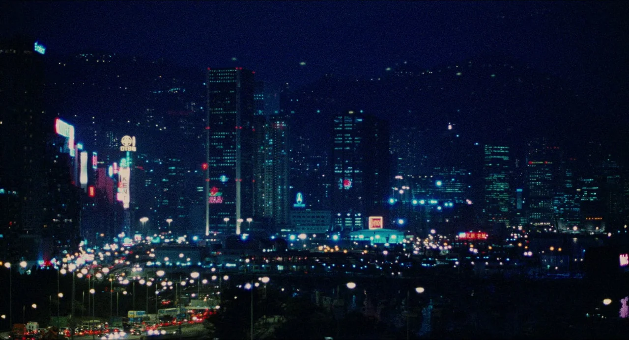 Rouge (1987) movie still: establishing — A dense urban skyline at night features numerous glowing skyscrapers and clustered street lighting. The…