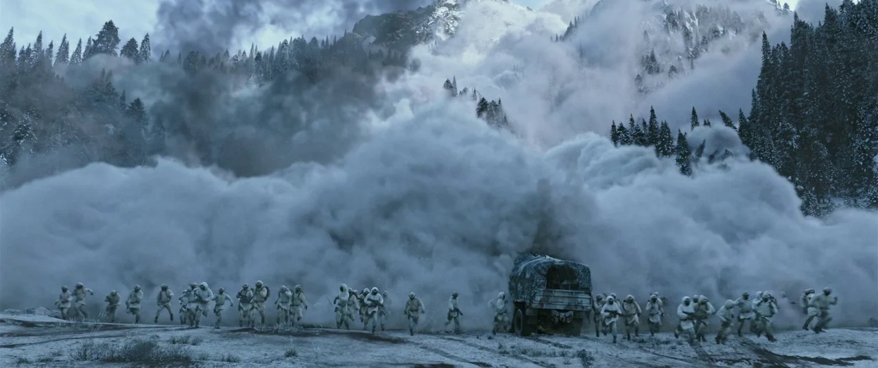 War for the Planet of the Apes (2017) movie still: wide — A group of soldiers in white camouflage gear run across a snow-covered mountain pass. A…