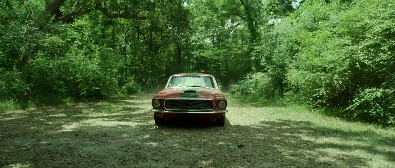 Universal Soldier: Day of Reckoning (2012) movie still: wide — A red vintage car rests on a narrow dirt trail winding through a dense forest.…