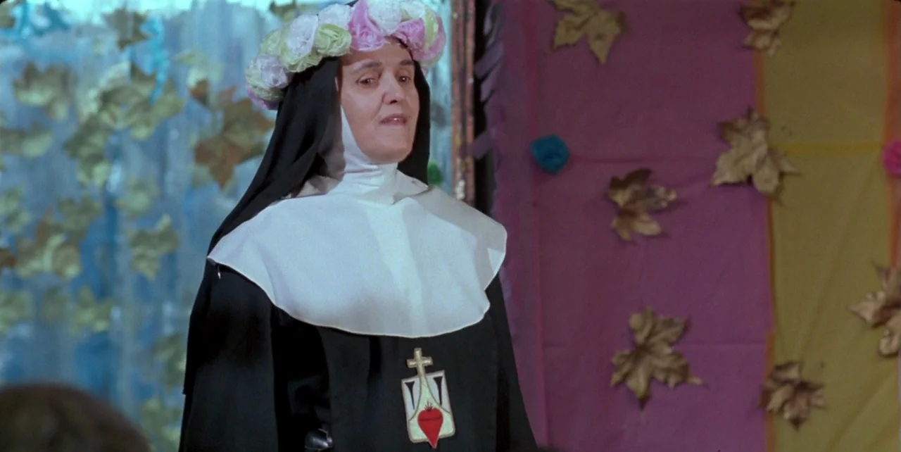 Dark Habits (1983) movie still: medium — A festive indoor space decorated with artificial leaves attached to colorful fabric wall panels. A nun…
