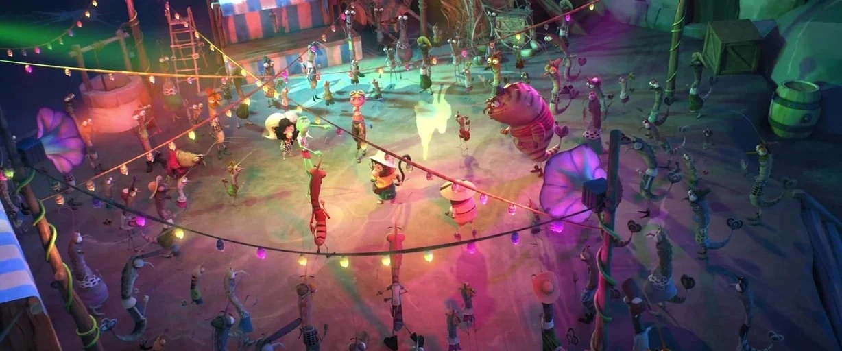 Around the World in 80 Days (2021) movie still: wide — A nighttime carnival setting features an outdoor clearing illuminated by draped multicolored…