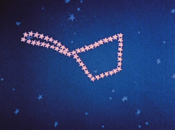 Rabbit’s Moon (1950) movie still: establishing — A deep blue night sky contains a constellation made of light pink star-shaped icons. No people or…