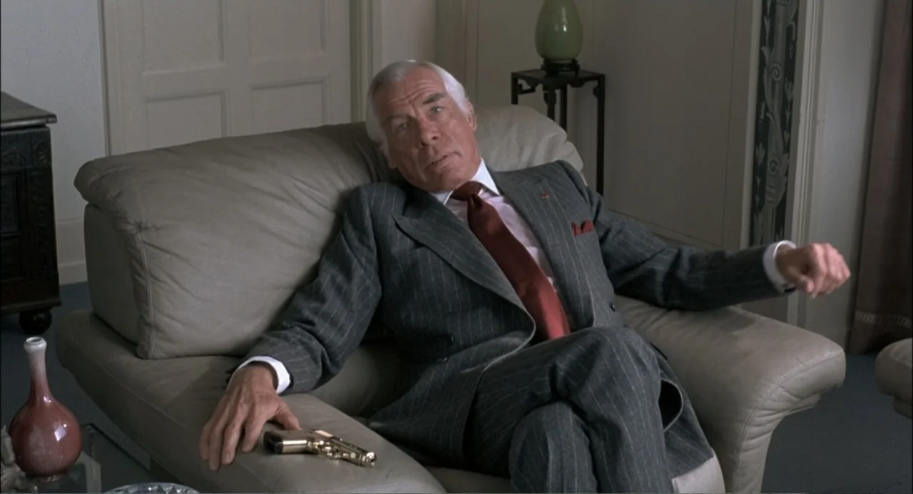 Gorky Park (1983) movie still: medium — A refined living room features beige leather furniture, light walls, and minimal decor. An older man in a…