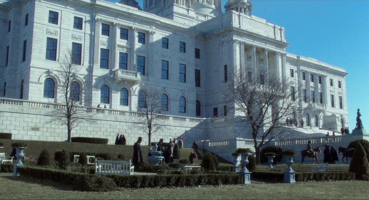 Amistad (1997) movie still: wide — A massive white neoclassical building stands behind a formal outdoor terrace with winter-bare trees. Small groups…