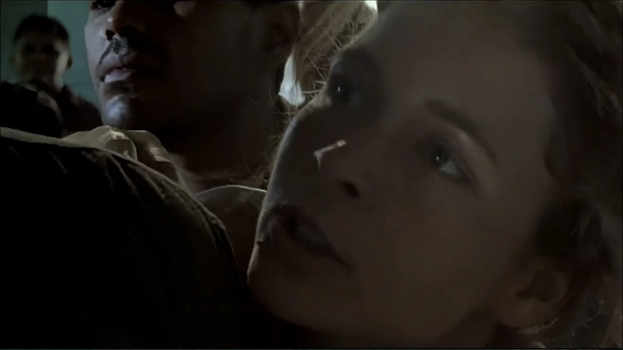 In the Middle of the World (1990) movie still: closeup — A dimly lit cabin of a moving vehicle at night with tight space. A woman rests her head…