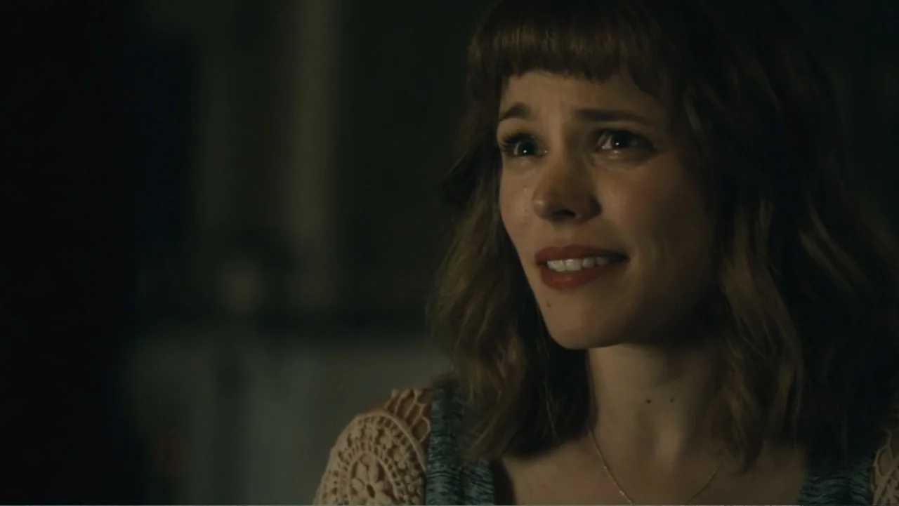 About Time (2013) movie still: closeup — An interior space is dimly lit with focus on the woman. She speaks while looking slightly away from the…