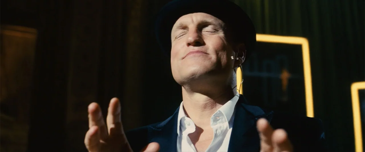 Now You See Me (2013) movie still: closeup — A man stands in a dark studio with glowing rectangular lights visible in the background. He holds his…